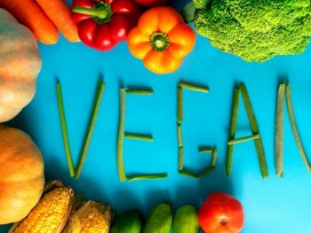 vegan spelled out with plant-based foods like fruits and vegetables
